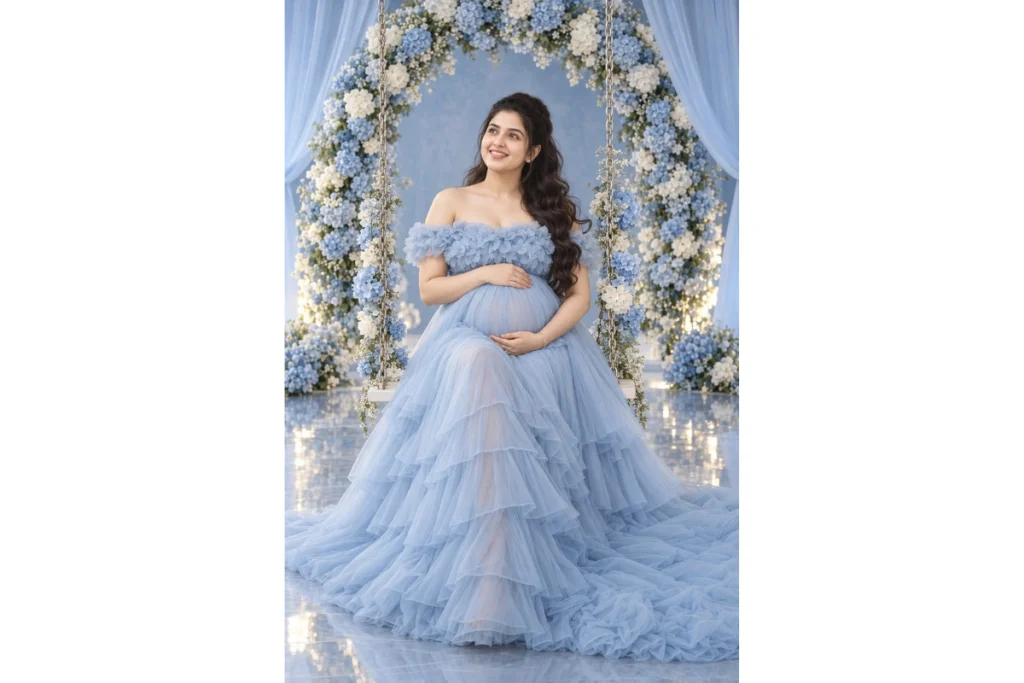 Pregnant woman wearing a powder blue off-shoulder maternity gown posing beneath a blue and white floral arch