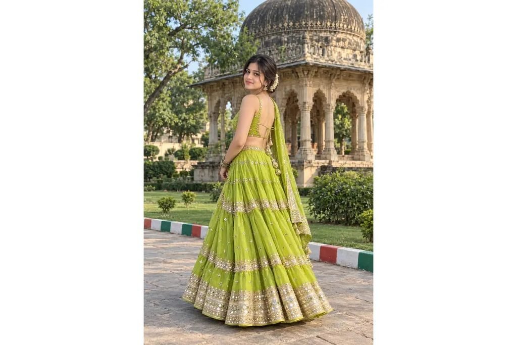 SEO-Friendly Alt Text: Lime green Gujarati Navratri lehenga choli with golden embroidered borders, traditional festive outfit for girls posing in a beautiful heritage garden with historic architecture