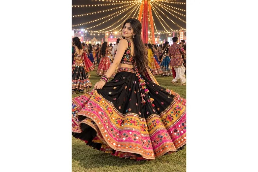 SEO-Friendly Alt Text: Black Gujarati Navratri mirror-work lehenga choli with colorful embroidered pink and orange borders, festive Garba night outfit for girls