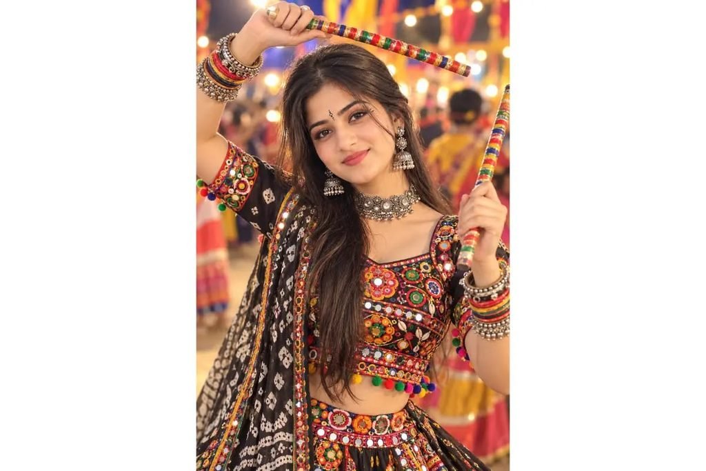 Gujarati Garba girl wearing a colorful mirror-work chaniya choli with a black and white patterned dupatta, silver jewelry and festive bangles for Navratri